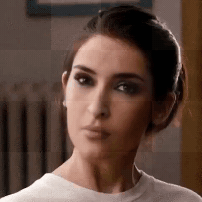 A Close Up Of A Woman 'S Face Wearing A White Shirt And Making A Funny Face . GIF