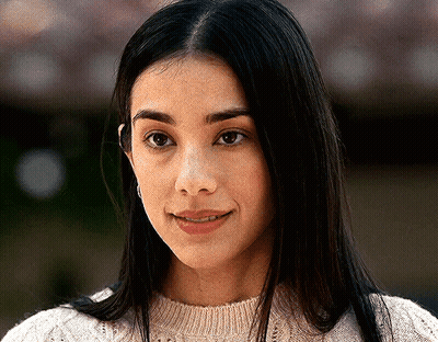 A Close Up Of A Woman 'S Face Wearing A White Sweater And Smiling . GIF