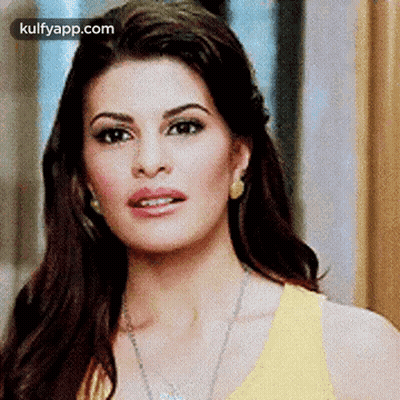 A Close Up Of A Woman 'S Face Wearing A Yellow Top And Earrings . GIF