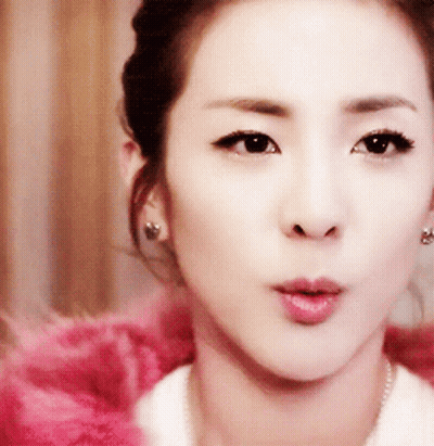 A Close Up Of A Woman 'S Face Wearing Earrings And A White Shirt GIF
