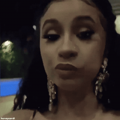 A Close Up Of A Woman 'S Face Wearing Earrings And Making A Funny Face . GIF