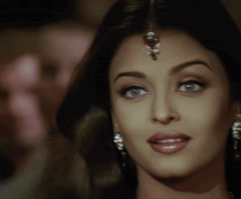A Close Up Of A Woman 'S Face With A Bindi On Her Forehead And Earrings . GIF