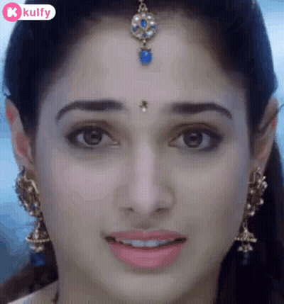 A Close Up Of A Woman 'S Face With A Bindi On Her Forehead And Earrings . GIF