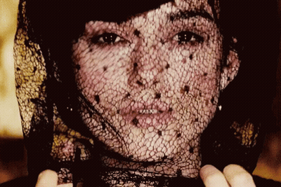 A Close Up Of A Woman 'S Face With A Black Lace Veil GIF