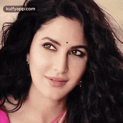 A Close Up Of A Woman 'S Face With A Black Spot On Her Forehead And A Pink Shirt . GIF