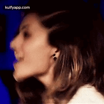 A Close Up Of A Woman 'S Face With A Blue Background And Earrings . GIF