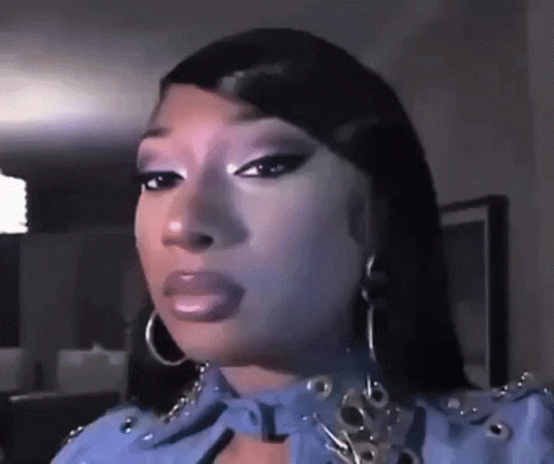 A Close Up Of A Woman 'S Face With A Blue Jacket And Hoop Earrings . GIF