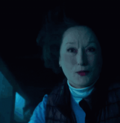 A Close Up Of A Woman 'S Face With A Blue Light Behind Her GIF