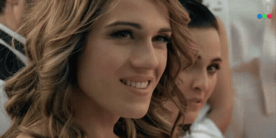 A Close Up Of A Woman 'S Face With A Blurred Image Of A Man In A Suit Behind Her GIF