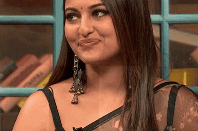 A Close Up Of A Woman 'S Face With A Bookshelf In The Background GIF