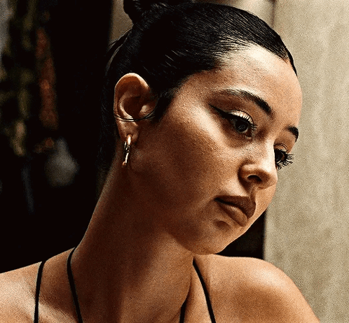 A Close Up Of A Woman 'S Face With A Bun And Earrings GIF