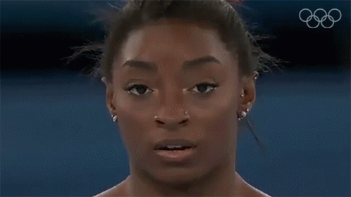 A Close Up Of A Woman 'S Face With A Bun In Her Hair And Earrings . GIF