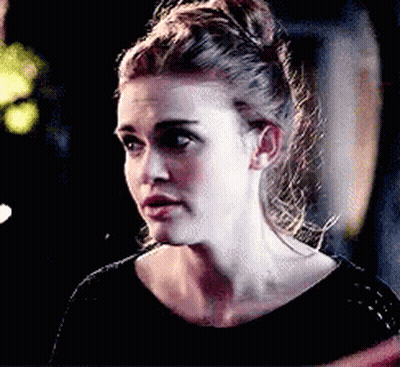 A Close Up Of A Woman 'S Face With A Bun In Her Hair . GIF