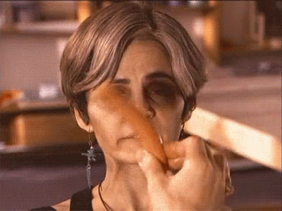 A Close Up Of A Woman 'S Face With A Carrot Sticking Out Of It GIF