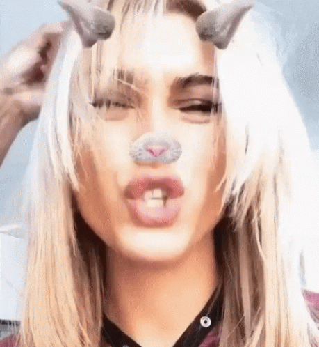 A Close Up Of A Woman 'S Face With A Cat Nose And Horns On Her Head . GIF