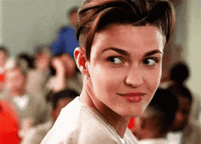 A Close Up Of A Woman 'S Face With A Crowd Behind Her GIF