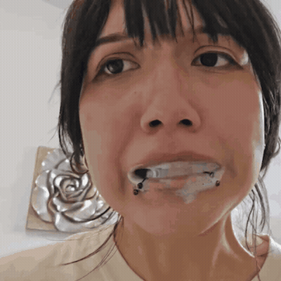 A Close Up Of A Woman 'S Face With A Few Drops Of Liquid In Her Mouth GIF