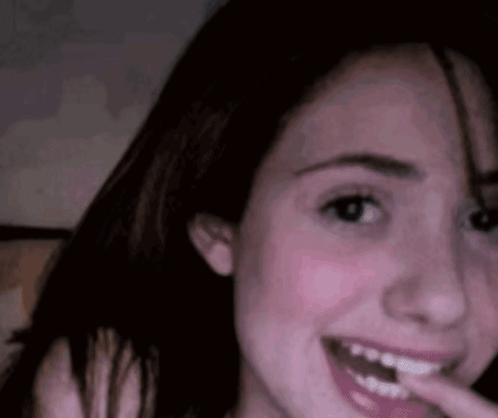 A Close Up Of A Woman 'S Face With A Finger In Her Mouth . GIF