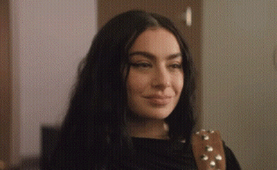 A Close Up Of A Woman 'S Face With A Guitar Strap Around Her Shoulder . GIF