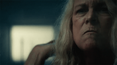 A Close Up Of A Woman 'S Face With A Hand On Her Ear In A Dark Room . GIF