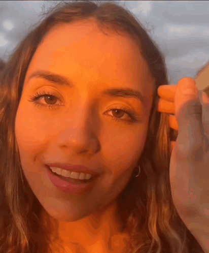 A Close Up Of A Woman 'S Face With A Hand On Her Head GIF