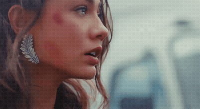 A Close Up Of A Woman 'S Face With A Leaf Earring GIF