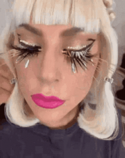 A Close Up Of A Woman 'S Face With A Lot Of Fake Eyelashes On Her Eyes . GIF