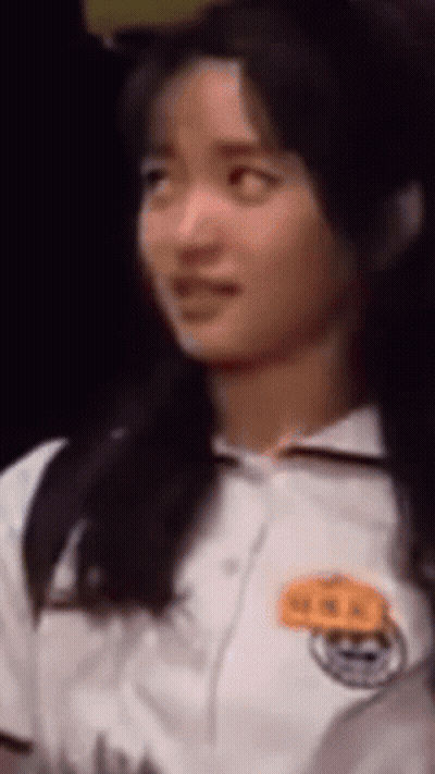 A Close Up Of A Woman 'S Face With A Name Tag On Her Chest GIF