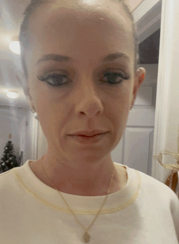 A Close Up Of A Woman 'S Face With A Necklace GIF