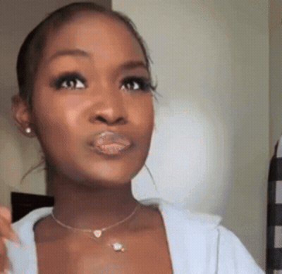 A Close Up Of A Woman 'S Face With A Necklace And Earrings . GIF
