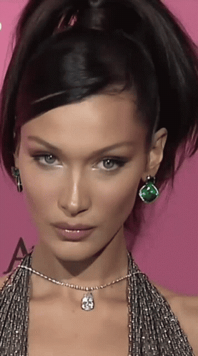 A Close Up Of A Woman 'S Face With A Necklace And Earrings GIF