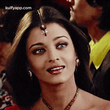 A Close Up Of A Woman 'S Face With A Necklace And Earrings On Her Head . GIF