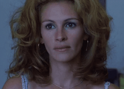 A Close Up Of A Woman 'S Face With A Necklace And Earrings GIF