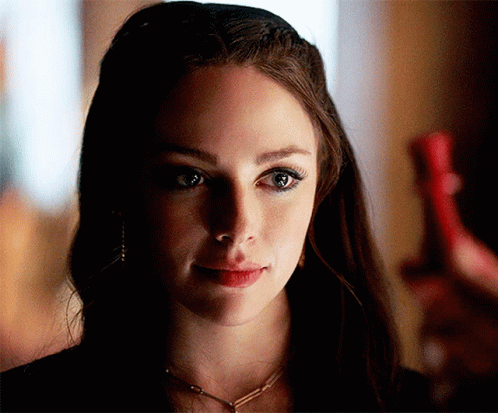 A Close Up Of A Woman 'S Face With A Necklace Around Her Neck GIF