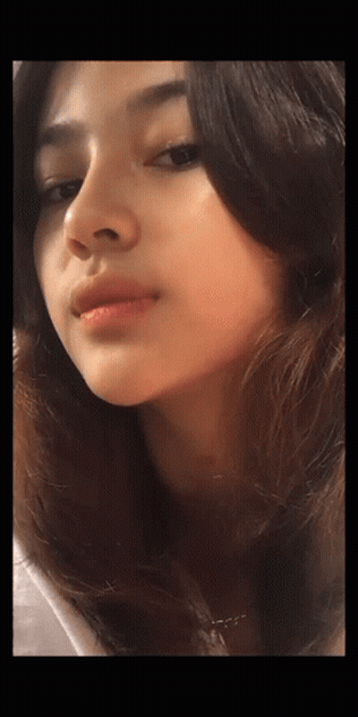 A Close Up Of A Woman 'S Face With A Necklace Around Her Neck GIF