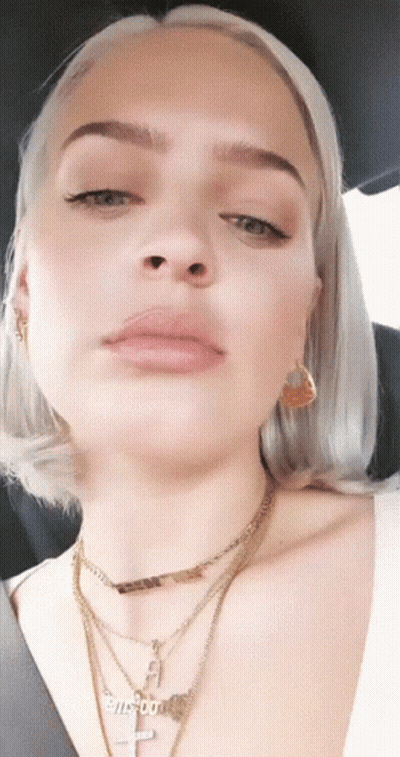 A Close Up Of A Woman 'S Face With A Necklace That Says Biscuits On It GIF