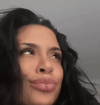 A Close Up Of A Woman 'S Face With A Piercing In Her Lip And Nose . GIF