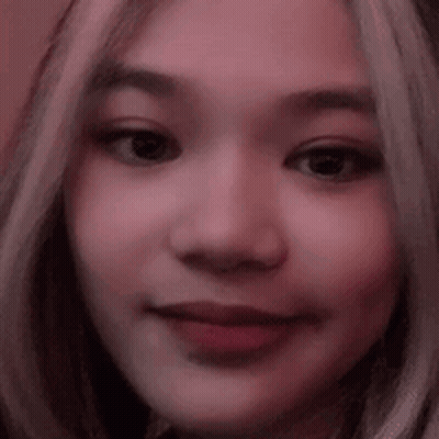 A Close Up Of A Woman 'S Face With A Pink Background And A Blurred Background . GIF