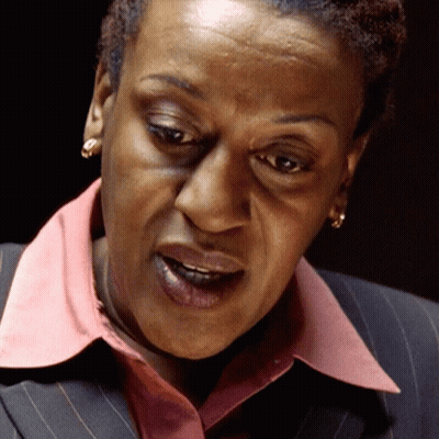 A Close Up Of A Woman 'S Face With A Pink Collar And Earrings GIF