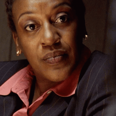 A Close Up Of A Woman 'S Face With A Pink Collar And Earrings GIF