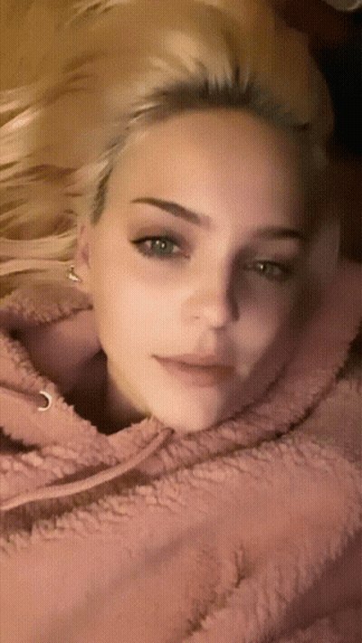 A Close Up Of A Woman 'S Face With A Pink Hoodie On GIF