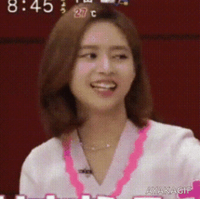 A Close Up Of A Woman 'S Face With A Pink Necklace Around Her Neck . GIF