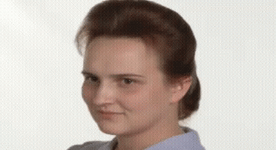 A Close Up Of A Woman 'S Face With A Ponytail And A Blue Shirt . GIF