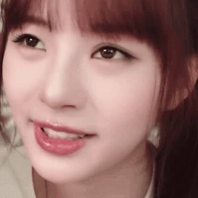 A Close Up Of A Woman 'S Face With A Ponytail And A Smile On Her Face . GIF