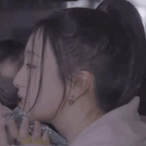 A Close Up Of A Woman 'S Face With A Ponytail And Earrings GIF