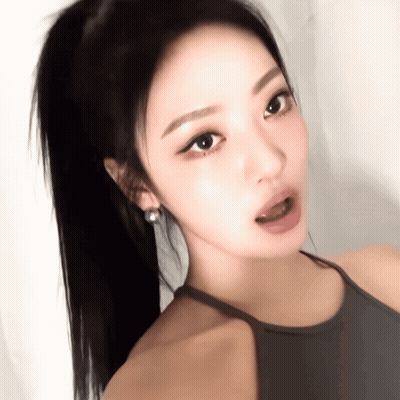 A Close Up Of A Woman 'S Face With A Ponytail And Earrings GIF