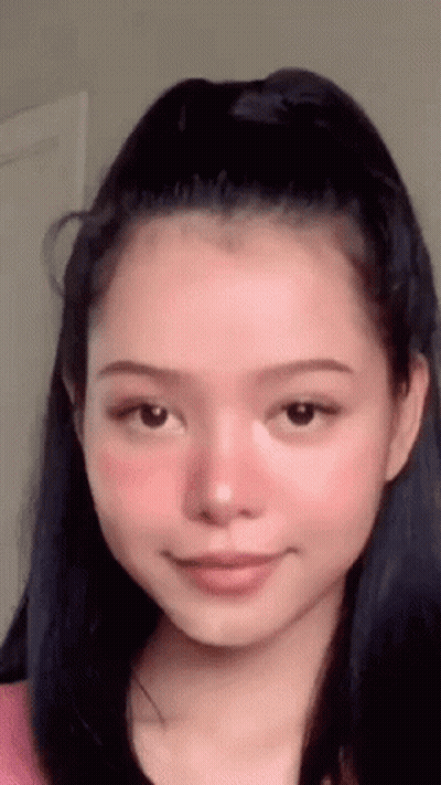 A Close Up Of A Woman 'S Face With A Ponytail And Pink Blush . GIF
