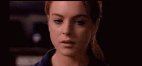 A Close Up Of A Woman 'S Face With A Ponytail In A Dark Room . GIF
