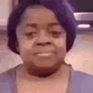A Close Up Of A Woman 'S Face With A Purple Hat And A Purple Shirt . GIF