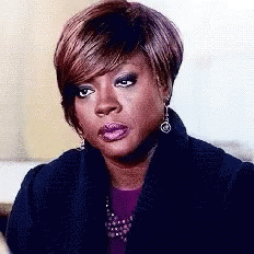 A Close Up Of A Woman 'S Face With A Purple Shirt And Earrings GIF